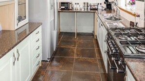 A kitchen with white cabinets, a stainless steel refrigerator, a gas stove, and a microwave. - 1 bedroom accommodation in Banchory (Banchory)