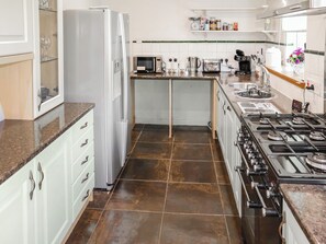 A kitchen with white cabinets, a stainless steel refrigerator, a gas stove, and a microwave. - 1 bedroom accommodation in Banchory (Banchory)