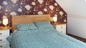 A bedroom with a wooden headboard, a floral-patterned bedspread, two bedside tables with lamps, and a nightstand with drawers. - 1 bedroom accommodation in Banchory (Banchory)