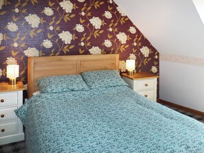 A bedroom with a wooden headboard, a floral-patterned bedspread, two bedside tables with lamps, and a nightstand with drawers. - 1 bedroom accommodation in Banchory (Banchory)