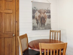 A wooden dining table with two chairs, a wooden door, and a wall-mounted picture of a yak. - 1 bedroom accommodation in Banchory (Banchory)