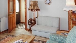 A living room with a sofa, a wooden table with magazines, a lamp, a spinning wheel, and a patterned rug. - 1 bedroom accommodation in Banchory (Banchory)
