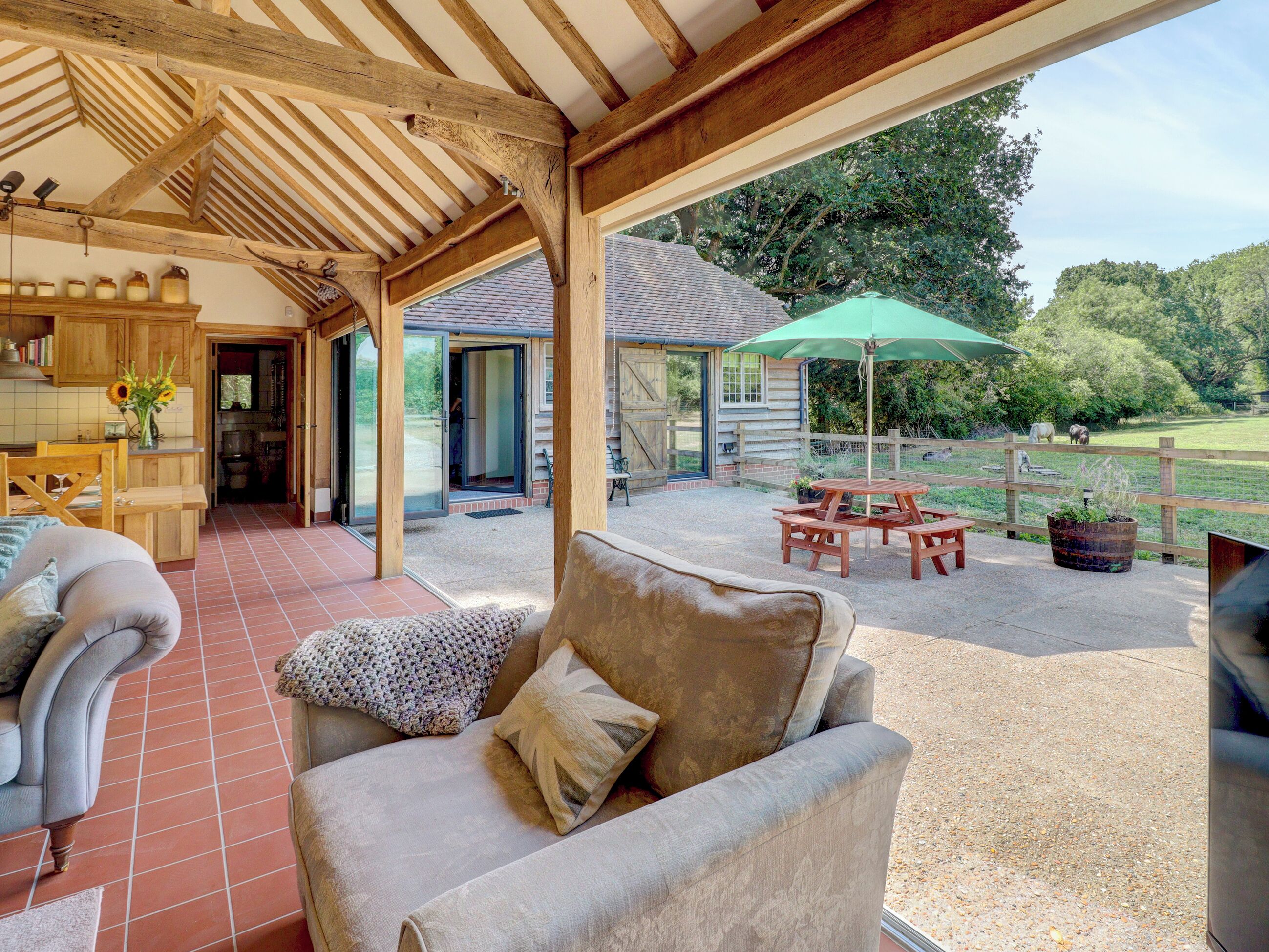 A covered patio area with a sofa, a table, and a green umbrella.