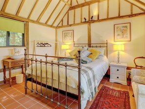 A bedroom with a four-poster bed, a bedside table with a lamp, a chair, and a window with a view of trees. - 2 bedroom accommodation in Steyning (Steyning)