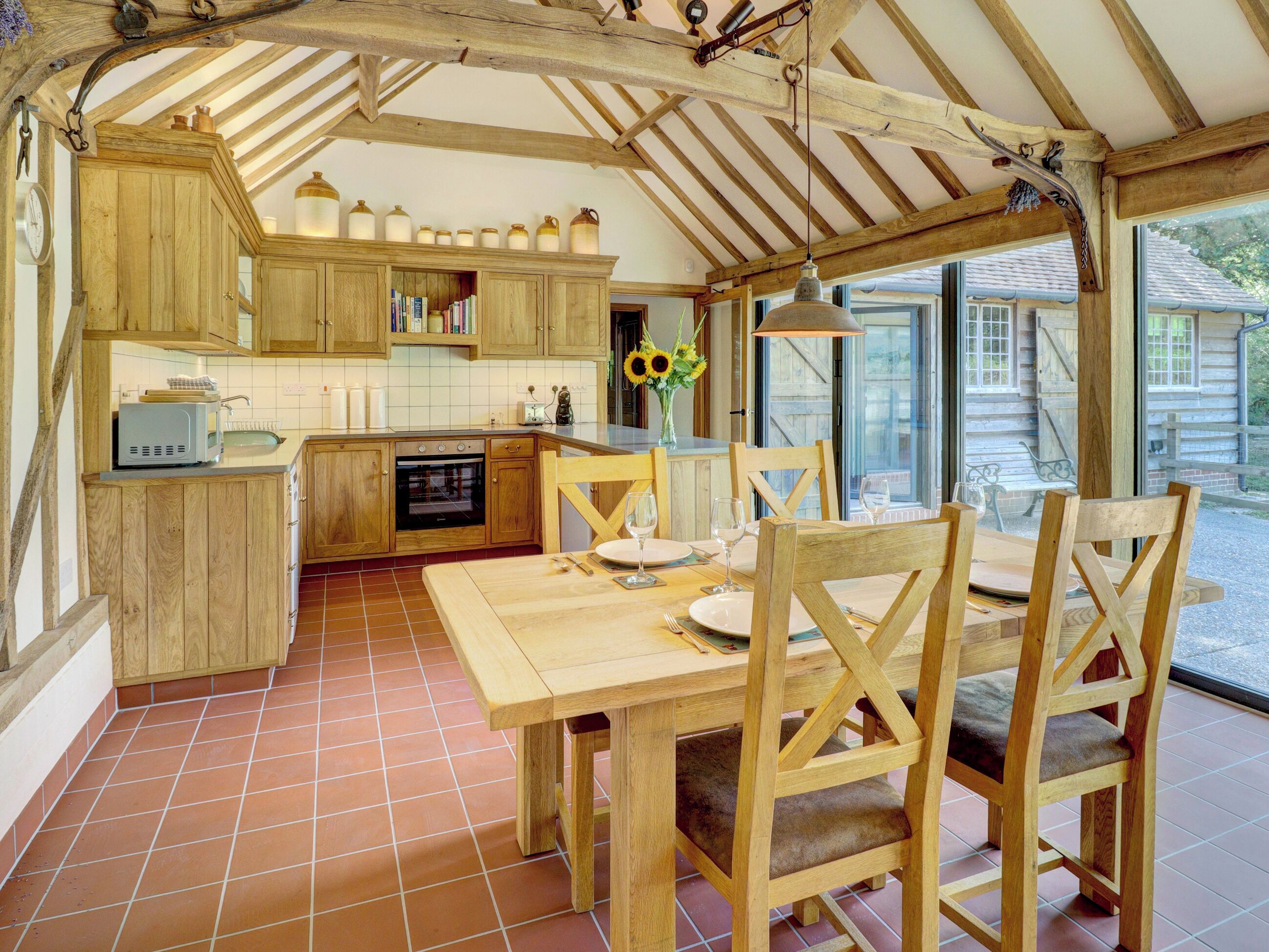 Une cuisine rustique avec des meubles de rangement en bois, une table à manger avec des chaises et une grande fenêtre.