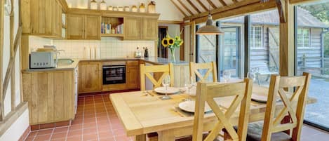 Una cocina rústica con armarios de madera, una mesa de comedor con sillas y un ventanal grande.