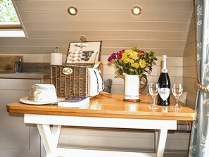 A table with a wicker basket, a white pitcher with flowers, a bottle of wine, and two glasses. - Kingfisher - UK52266 (Sidmouth)