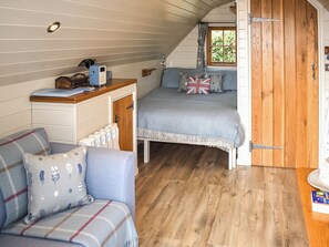 Une pièce confortable avec un lit, un petit bureau, une chaise et une fenêtre avec des rideaux.