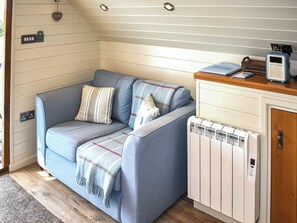 A cozy room with a sofa, a radiator, and a wooden cabinet. - Kingfisher - UK52266 (Sidmouth)