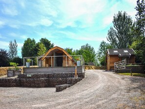 A wooden cabin with a sloped roof, a gravel driveway, and a stone wall. - Kingfisher - UK52266 (Sidmouth)