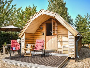 Eine Holzhütte mit Veranda, Tisch, zwei Stühlen und Sonnenschirm.