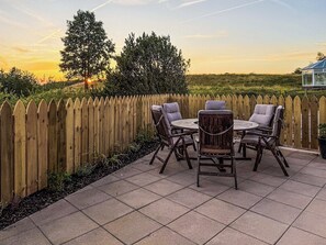 Une terrasse extérieure avec une clôture en bois, une table ronde et quatre chaises.