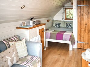 Ein gemütliches Zimmer mit einem Bett, einem kleinen Schreibtisch, einem Stuhl und einem Fenster mit Vorhängen.