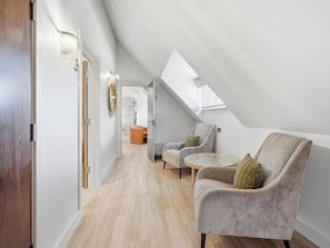 A modern loft bedroom with a sloped ceiling, a wooden floor, and a view of the city. - The Penthouse - UK52276 (Beccles)