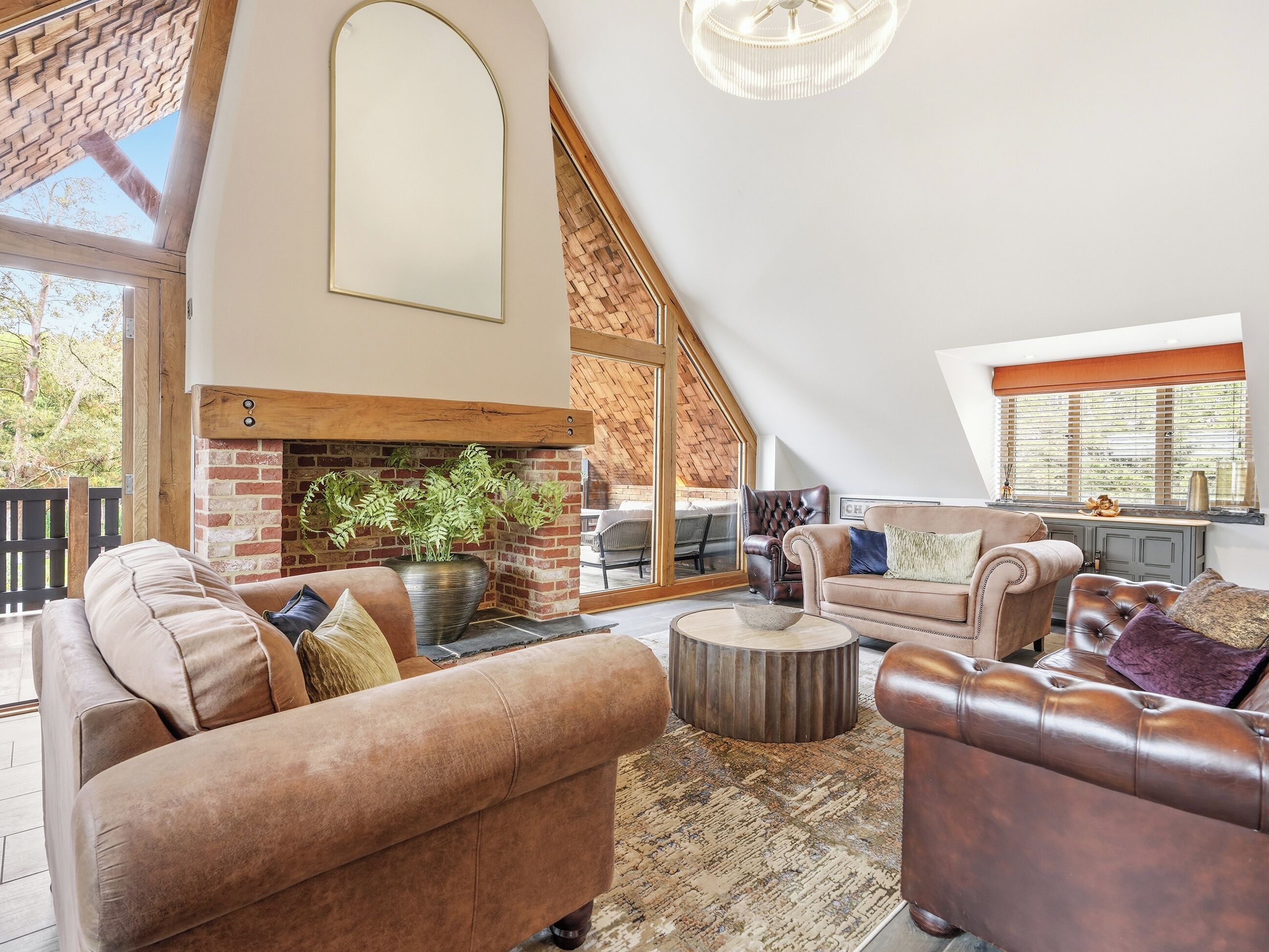 A spacious living area with a fireplace, leather sofas, and a large window.