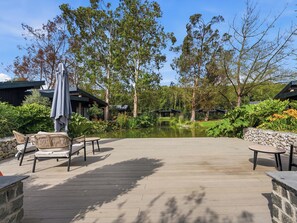 A wooden deck with outdoor seating, a pond, and surrounding trees. - The Penthouse - UK52276 (Beccles)