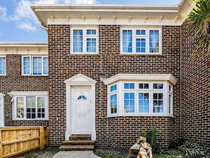 A two-story brick house with a white front door, a small porch, and a window with a bay window. - 3 bedroom accommodation in Shanklin (Shanklin)