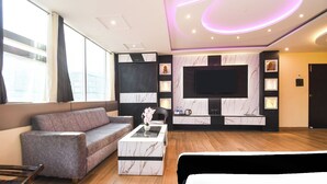 Een moderne woonkamer met een bank, salontafel en een aan de muur bevestigde televisie.