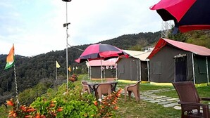 A campsite with tents, a table, chairs, and a flag. - Prince Campsite (Chail)
