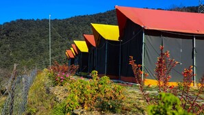 A row of tents with red roofs, set against a backdrop of a hilly landscape. - Prince Campsite (Chail)