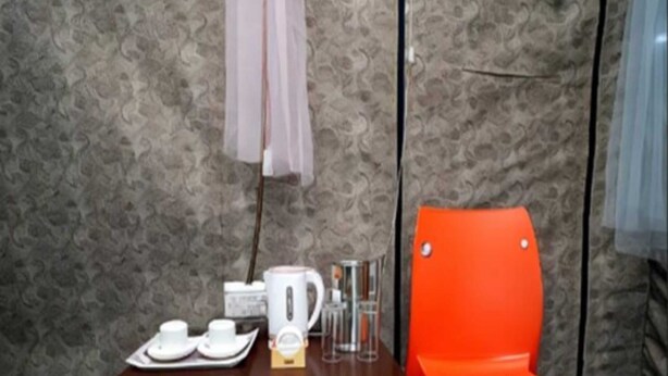 A small table with a white coffee maker, cups, and a tray, next to a bright orange chair. - Prince Campsite (Chail)