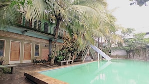 A swimming pool with a wooden deck, a staircase, and a building with doors and windows. - Penginapan Asri Syariah (Kepanjen)