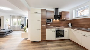 Una cocina moderna con electrodomésticos integrados, un área de comedor con sofá y vistas al exterior por una ventana.