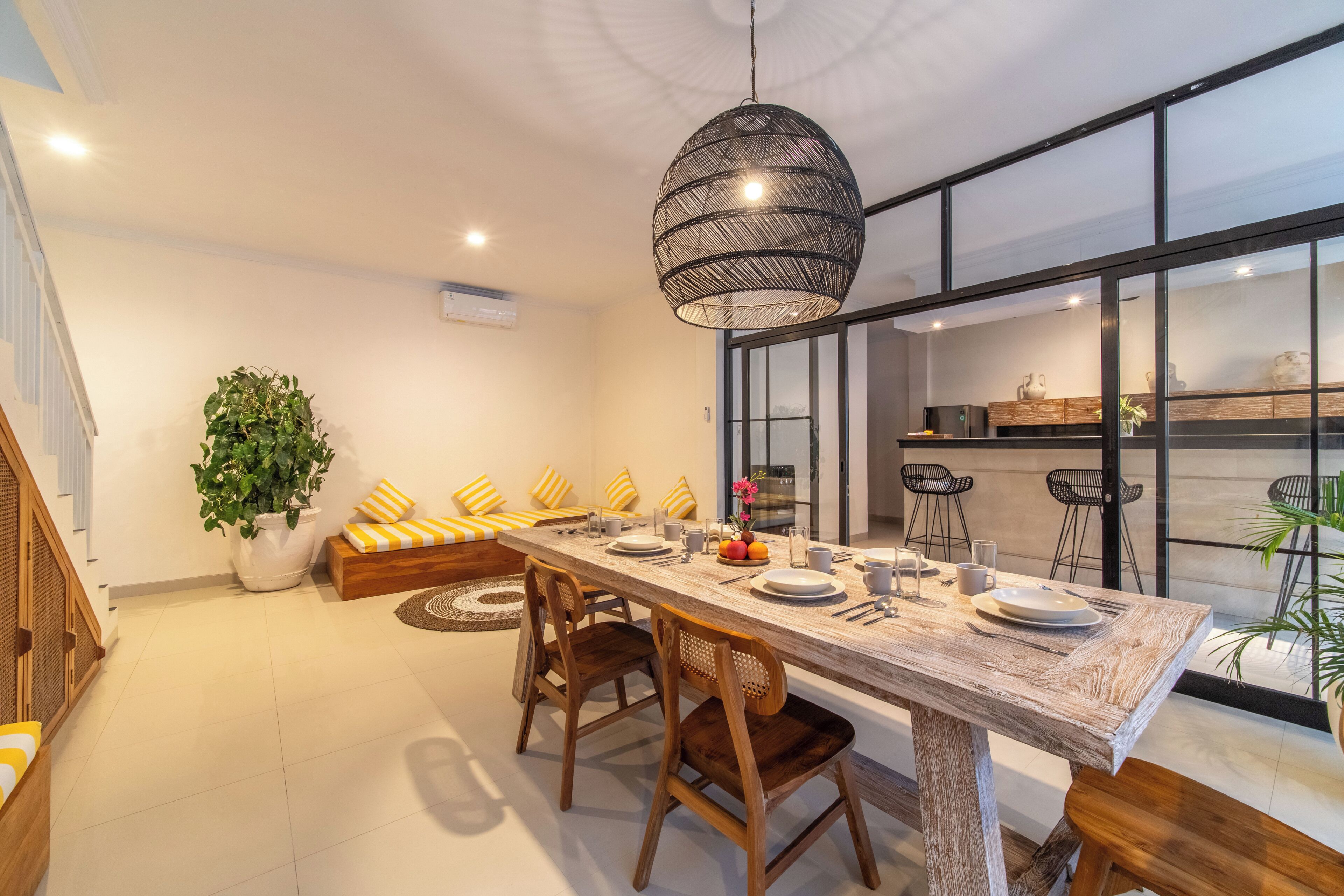 Un comedor moderno con una mesa larga, sillas de madera y una lámpara colgante.