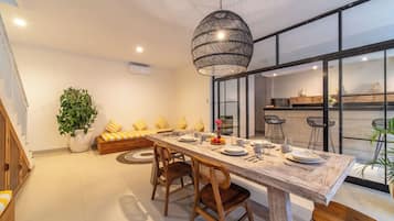 Un comedor moderno con una mesa larga, sillas de madera y una lámpara colgante.