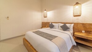 Habitación de hotel con una cama grande, cabecera de madera, dos lámparas de pared y un enchufe en la pared.