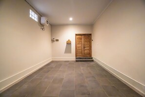 A hallway with a tiled floor, a wooden door, and a small shrine on the wall. - Bougenvia Villa (Badung)