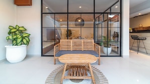 Un interior moderno con comedor que incluye una mesa y sillas de madera, una planta grande en maceta y un separador de vidrio.