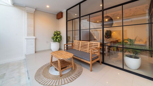 Una habitación con un banco de madera, una mesita pequeña y una planta grande en maceta.
