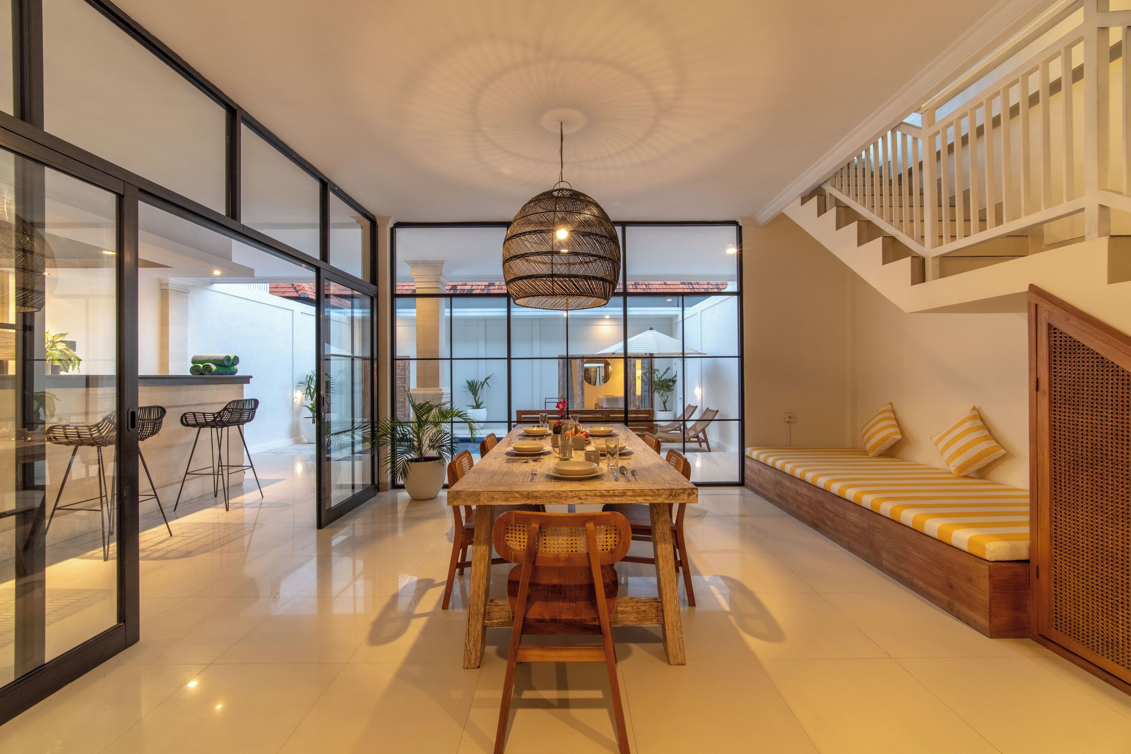 A spacious dining area with a wooden table and chairs, a hanging light fixture, and a view of the outdoor patio through large glass doors.