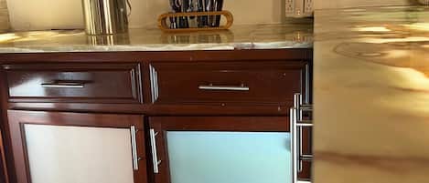 A kitchen with wooden cabinets, a stainless steel kettle, and a coffee maker.