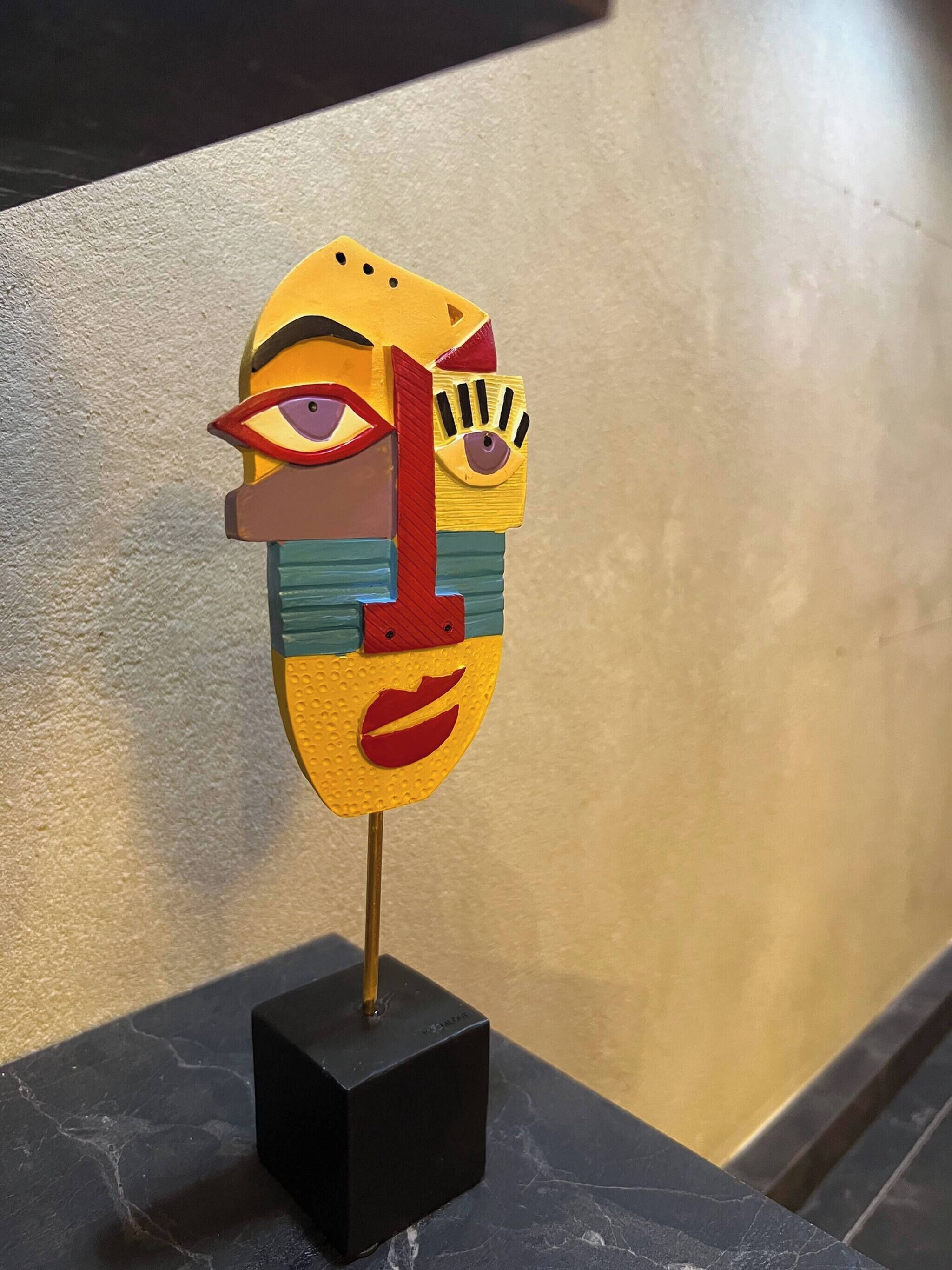 A colorful abstract sculpture on a black pedestal.