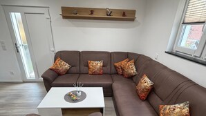A modern living room with a brown sectional sofa, a white coffee table, and decorative pillows. - Modern Apartment “Frankenruhe” near Bamberg on the Edge of Franconian Switzerland (Strullendorf)