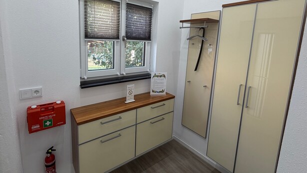 A room with a window, a wooden counter, a cabinet, a wardrobe, and a fire extinguisher. - Modern Apartment “Frankenruhe” near Bamberg on the Edge of Franconian Switzerland (Strullendorf)
