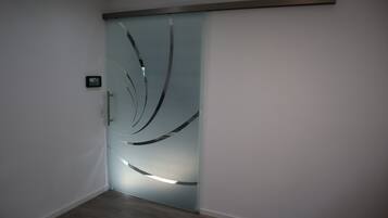 Ein modernes Interieur mit einer Schiebeglastür, die einen dekorativen Metallrahmen und ein kleines, an der Wand befestigtes Gerät aufweist.