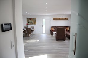 A modern living room with a sofa, a dining area with a table and chairs, and a painting on the wall.