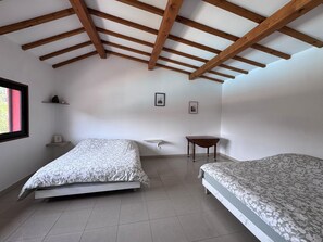 A bedroom with two beds, a small table, and a window. - Private cottage in the heart of the Vosges (Allarmont)