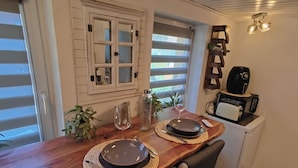Un coin repas avec une table en bois dressée pour deux personnes, un four à micro-ondes et un petit réfrigérateur.