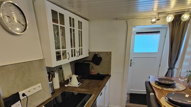 Une cuisine compacte dotée d’un plan de travail en bois, de meubles blancs et d’un four encastré.