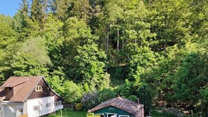 Un quartier résidentiel comprenant une maison, un petit abri de jardin et un jardin bien entretenu, agrémenté de haies et d’une pelouse.