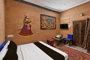 Una habitación de hotel con una cama, una mesita con un hervidor, una silla, un televisor y un mural grande en la pared.