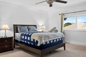 Une chambre à coucher avec un lit, une table de chevet, une lampe et une fenêtre donnant sur un beau paysage.