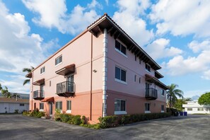 A multi-story building with balconies, a flat roof, and a clear sky. - 1 Block To Beach • Walk To Shops + Dining | Pet Friendly | Poinciana (Lauderdale-by-the-Sea)