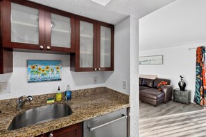 A modern kitchen with granite countertops, stainless steel appliances, and wooden cabinets. - 1 Block To Beach • Walk To Shops + Dining | Pet Friendly | Poinciana (Lauderdale-by-the-Sea)