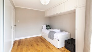 Ein Schlafzimmer mit Bett, einer Kommode, einer Pendelleuchte und Holzboden.
