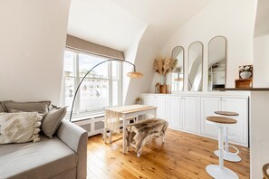 A cozy living room with a sofa, a wooden table, and a pet dog. - Stylish Hyde Park & Paddington Stay (London)
